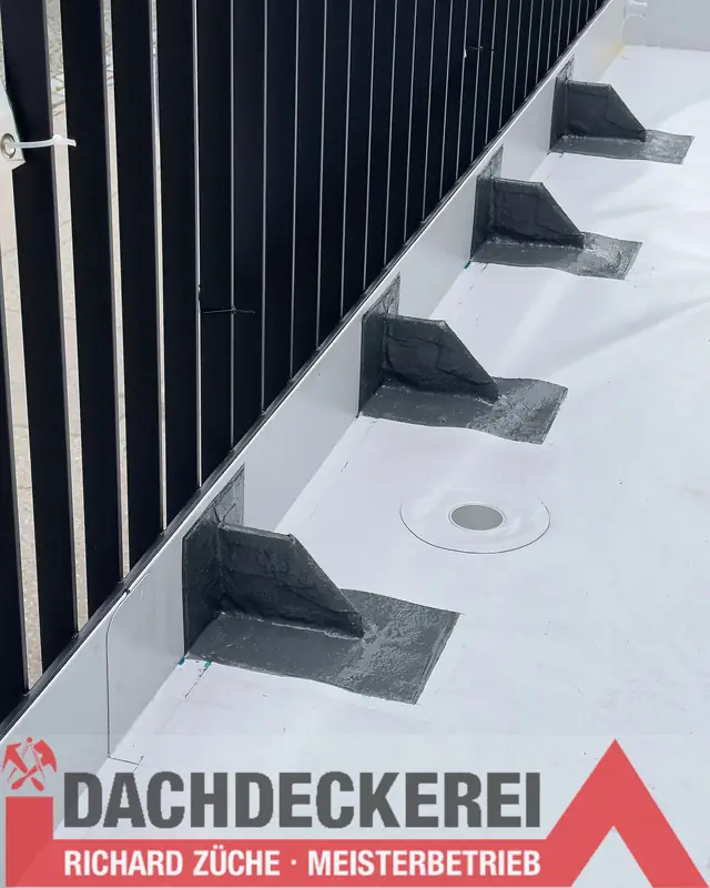 Abgedichtete Geländerbefestigungen und Dachablauf auf einem hellen Flachdach